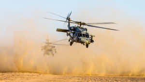 兩架軍用直升機低空飛越塵土飛揚的沙漠景觀。 — 藍天 壁紙