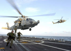 水兵在航空母艦上奔跑，直升機在海洋上空起飛。 — 桌面 壁紙