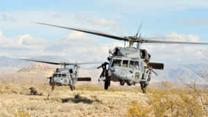 兩架軍用直升機低空飛越沙漠，背景有山脈。 — 直升機 壁紙
