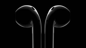 兩款黑色耳塞在黑色背景上直立，帶有攝影棚燈光。 — AirPods 壁紙