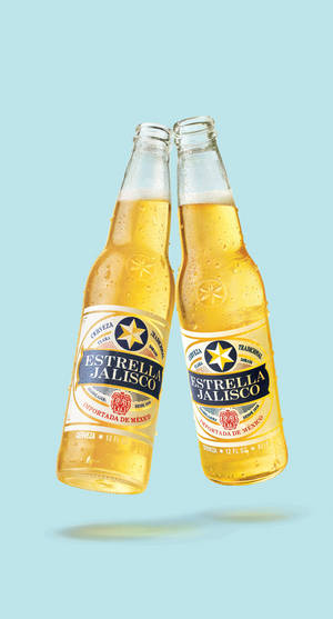 兩瓶Estrella Jalisco啤酒在藍色背景上碰撞，帶有冷凝水滴。 — 啤酒 壁紙
