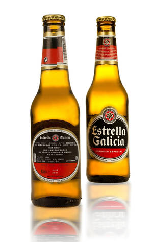 兩瓶Estrella Galicia啤酒，標籤朝前，放在白色反射表面上。 — Moto Pad 60 Pro 壁紙
