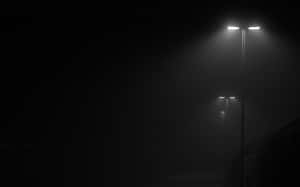 夜晚空蕩的城市場景中，兩盞街燈穿過濃霧閃耀。 — 黑色桌面 壁紙