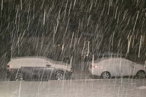 夜間暴風雪中，兩輛停在外面的積雪汽車。 — 夜晚 壁紙