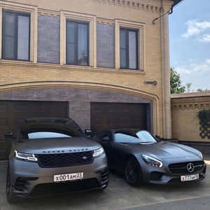 兩輛啞光灰色豪華車停在豪宅車庫前。 — 1:1 壁紙