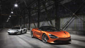 兩輛McLaren超級跑車停放在昏暗的工業倉庫中。 — iMac 壁紙