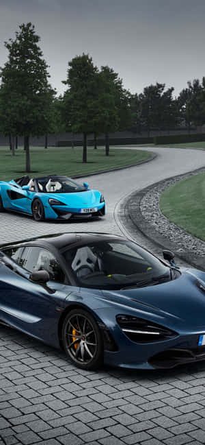 兩輛McLaren跑車停放在石路上，背景有樹木。 — Pixel 7 Pro 壁紙
