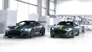 兩輛灰色Aston Martin賽車帶有綠色條紋，在乾淨的工業車庫中。 — 奧斯頓馬丁 壁紙
