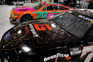 兩輛帶有鮮豔貼花的NASCAR賽車停放在車庫中。 — 橘色 壁紙