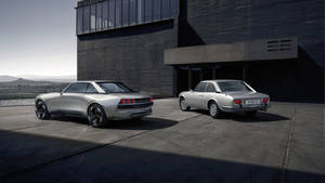 兩輛銀色跑車停在一棟現代建築前，背景有山脈。 — Mercedes Benz C300 壁紙