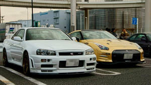 兩輛改裝的日產Skyline GT-R跑車停在天橋下的城市街道上。 — 汽車 壁紙