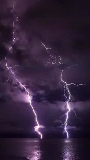 兩道強勁的閃電照亮了水面上黑暗的暴風雨之夜。 — 閃電 壁紙