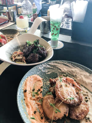 兩道擺盤精美的美食菜餚，包括炸雞和釉面肉，飾以香草和醬汁。 — 3:4 壁紙