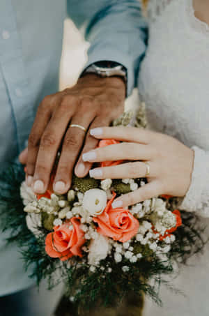 情侶戴著結婚戒指的手捧著花束。 — 2:3 壁紙