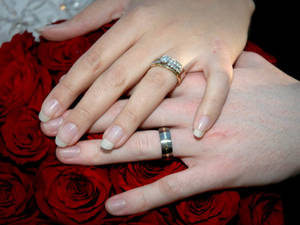 情侶的手在紅玫瑰上交握，戴著結婚戒指。 — 結婚戒指 壁紙