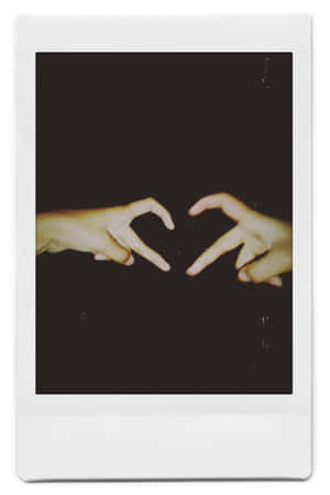 兩隻手在黑暗背景下形成心形，放在Polaroid相框中。 — 拍立得 壁紙