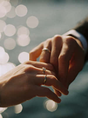 兩隻手在陽光下互相握持，戴著結婚戒指。 — 婚禮 壁紙