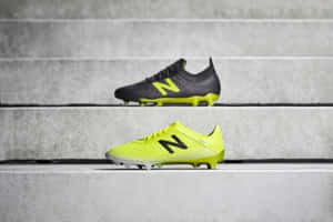 兩雙New Balance足球鞋放在混凝土台階上，一雙螢光黃色，一雙黑色。 — New Balance 壁紙