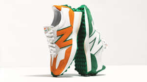 兩雙色彩繽紛的 New Balance 運動鞋，帶有橙色、綠色和白色點綴，直立於白色表面上。 — New Balance 壁紙