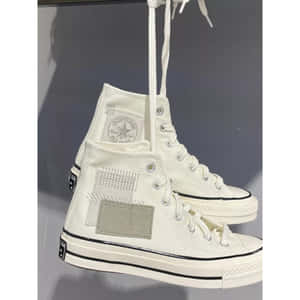 白色高筒Converse運動鞋帶有補丁細節，懸掛在灰色背景上。 — Converse 壁紙