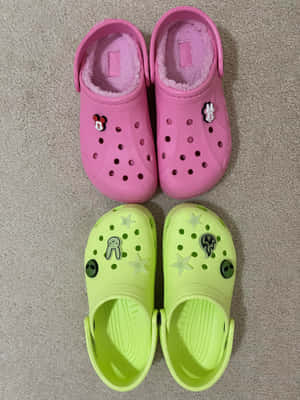 兩雙兒童Crocs鞋，帶有角色飾物，放在地毯上。 — iPad 第9代 壁紙