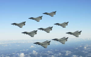 八架戰鬥機在雲層上方編隊飛行，晴朗藍天。 — 軍事動圖 壁紙