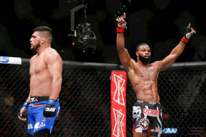 八角籠內兩名MMA拳手，一名勝利高舉雙臂，另一名在場館燈光下垂頭喪氣地站著。 — 拳擊 壁紙