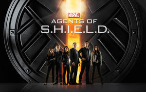 六名 S.H.I.E.L.D. 特工在發光的標誌前擺姿勢，背景熾熱。 — 漫威標誌 壁紙