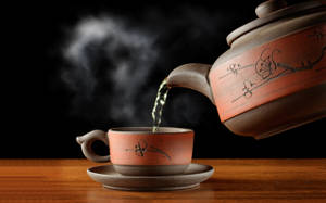 熱茶從陶瓷茶壺倒入木質表面上的相配杯子中。 — 茶 壁紙