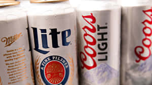 帶有冷凝水滴的冰凍啤酒罐，展示Miller Lite和Coors Light品牌。 — 麥迪遜·比爾 壁紙