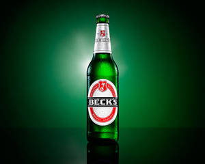 冰涼的 Beck's 啤酒瓶在深綠色反光表面上凝結水珠。 — 德國 壁紙