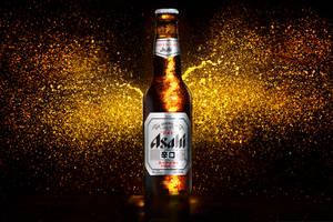 冰涼的Asahi啤酒瓶，金色液體飛濺，黑暗背景。 — 日本 壁紙