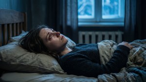 一名女子在床上，在雪窗的藍光下顯得憂慮。 — 憂鬱美學 壁紙
