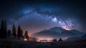 一群人在星空下舉起雙臂，背景是積雪的山峰和松樹。 — 山脈 壁紙