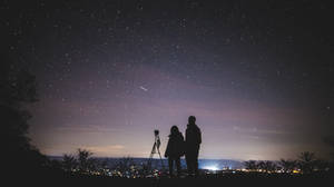 情侶用望遠鏡在夜晚觀看城市燈光上的星星 — 情侶 壁紙