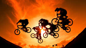 BMX車手在半空中，背景是鮮豔的橙色日落天空。 — 酷炫足球 壁紙