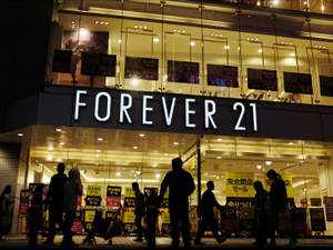 夜晚場景，人們走過一間有日本促銷標誌的 Forever 21 商店。