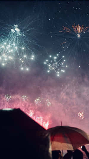 撐傘的人們觀看煙火照亮夜空。 — 新年快樂 壁紙