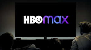 人們在黑暗的影院中觀看大螢幕上的HBO Max標誌。 — HBO 壁紙