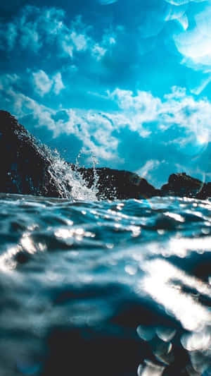 海浪拍打深色岩石，上方是明亮的藍天和白雲。 — 藍天 壁紙