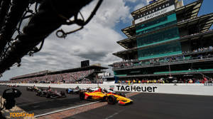 IndyCar 賽車在賽道上飛馳，看台座無虛席，天空多雲。 — 賽車 壁紙