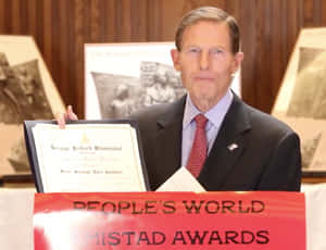 參議員理查德·布盧門撒爾在People's World Mistad Awards活動中手持獎狀。 — 桌面 壁紙