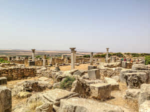 古代石頭遺跡，有柱子和散落的石塊，在晴朗的藍天下。 — 石頭 壁紙