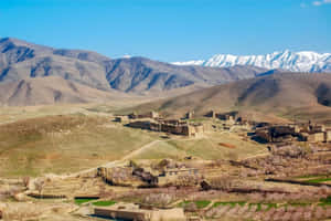 古老石堡壘在春季山景中，背景有白雪覆蓋的山峰。 — 阿富汗 壁紙