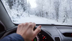 手握方向盤在積雪森林道路上行駛 — 冬季風景 壁紙