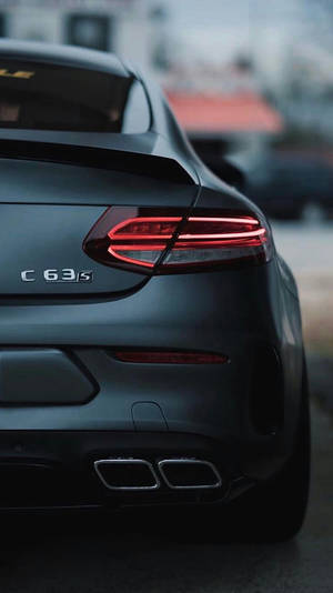 啞黑色 Mercedes-AMG C63 S 跑車的後視圖，帶有發光的紅色尾燈和雙排氣管。 — Mercedes Amg iPhone 壁紙