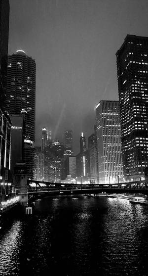 夜間城市天際線，燈火通明的摩天大樓和河流倒影。