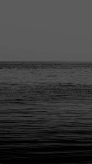 單色海洋波浪在沉悶的天空下與朦朧的地平線相遇。 — 海洋藍 壁紙