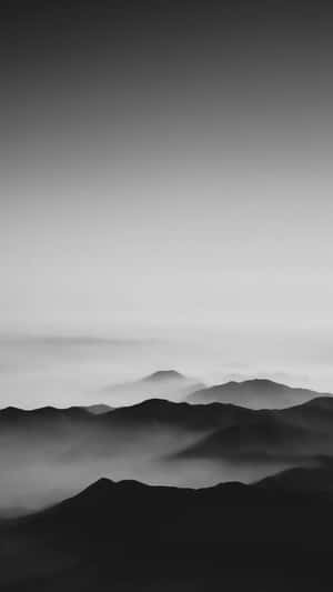 在漸變天空下，寧靜的黑白山脈籠罩在薄霧中。 — 簡約暗黑美學 壁紙