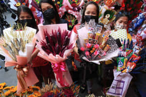 四位戴著口罩的女性在街市上拿著各式各樣的花束和糖果花束。 — 情人節快樂 壁紙